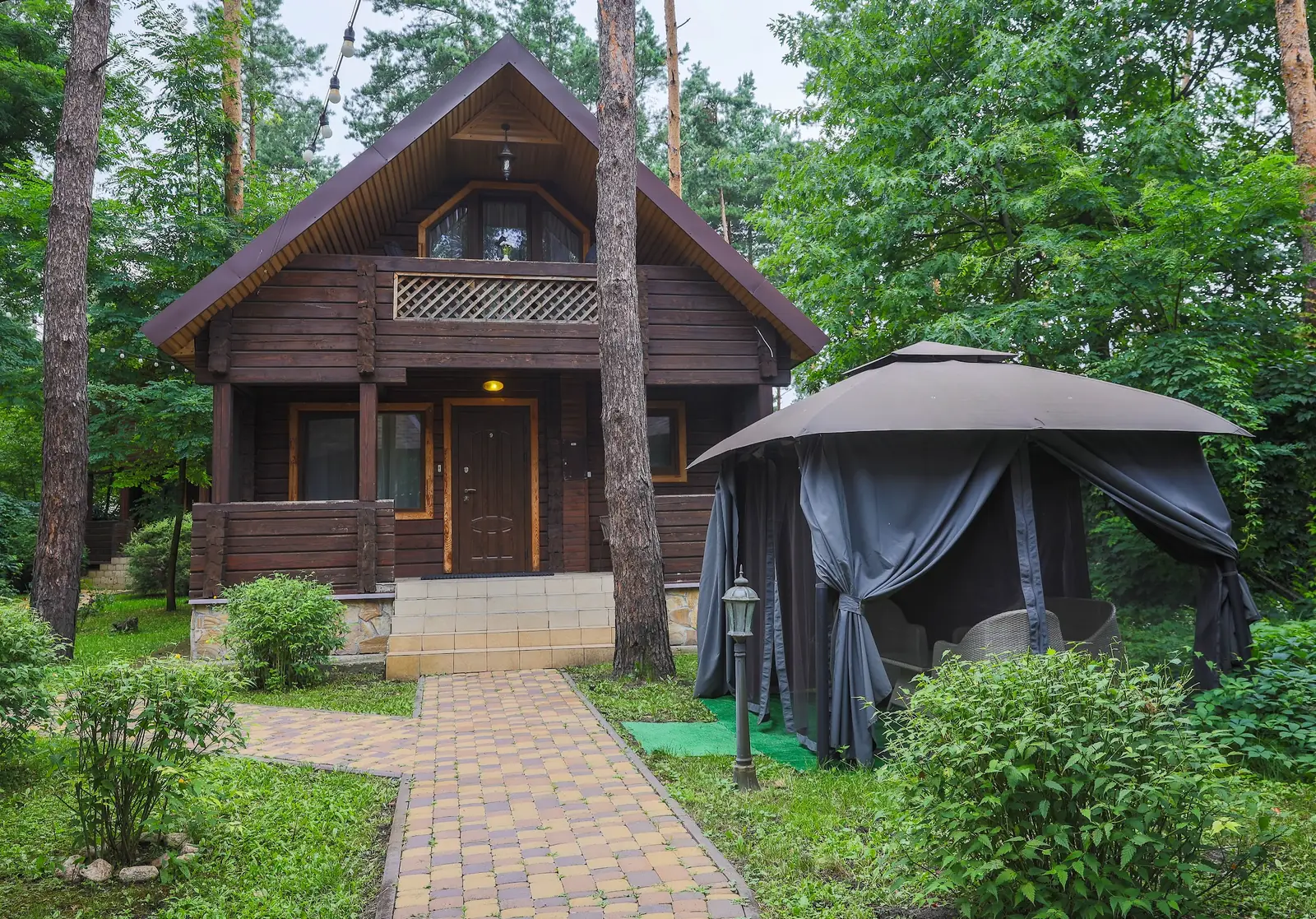 A wooden Villa Vita cottage with a gazebo by the entrance