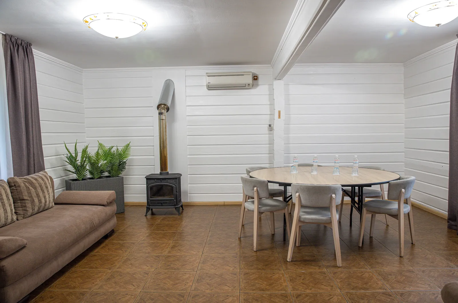 A living room with a fireplace and a dining area in a Villa Vita cottage